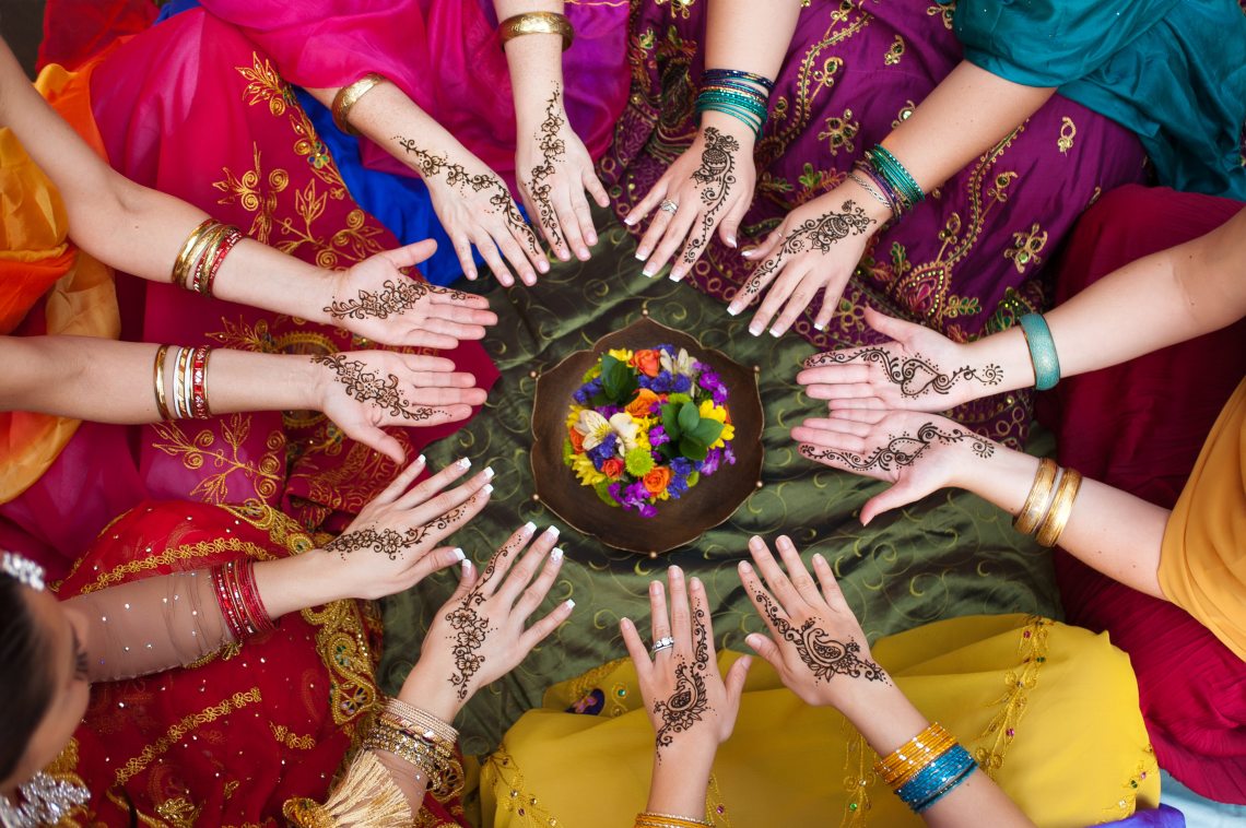 Ladies in Saris with colourful bangles and beautifully designed hennas